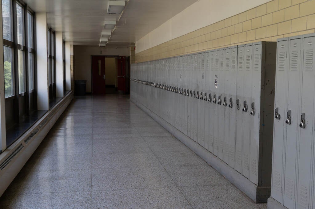 A long hallway in a school, with a wall of lockers.