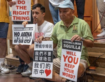 People hold signs that read Councilmember Squilla will you keep your word? Another person holds a sign written in Chinese.