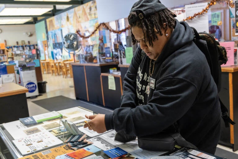 Di Hargrove, an ACLU community ambassador, hands out 'Know Your Rights' pamphlets and many other resources at and around the the Cecil B. Moore Library in North Philadelphia. (Kimberly Paynter/WHYY)