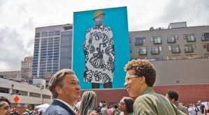 Realist painter Bo Bartlett talks with artist Amy Sherald (right) at the dedication of Sherald’s mural portrait of young Philadelphian, Najee Spencer-Young. (Kimberly Paynter/WHYY)