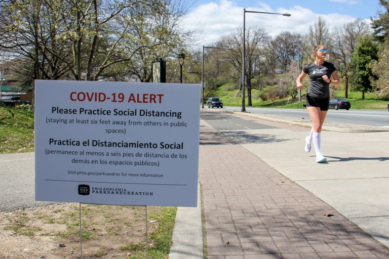 Signs posted along Philadelphia's Schuylkill River Trail caution users to keep six feet away from others to prevent the spread of COVID-19. (Emma Lee/WHYY)