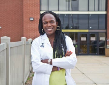 Dr. Ala Stanford stands in front of a health clinic with her arms crossed