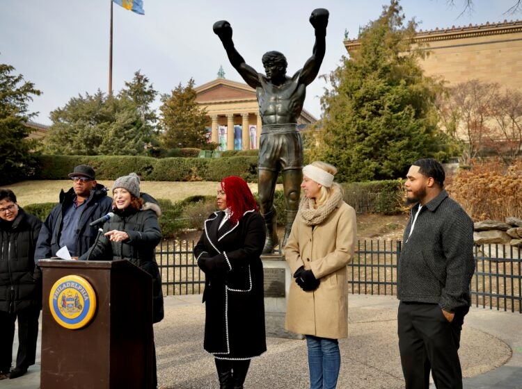 Several people standing behind a podium placed in front of the Rocky statue