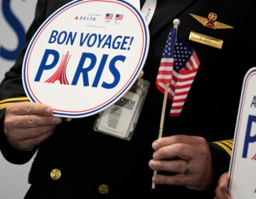 A pilot holds a bon voyage sign as some athletes from the United States depart from the airport, Wednesday, July 17, 2024, in Atlanta. Delta Air Lines celebrated members of Team USA on Wednesday at Hartsfield–Jackson Atlanta International Airport before the athletes flew to Paris for the Summer Games. The opening ceremony for the Games is scheduled for July 26. (AP Photo/Brynn Anderson)