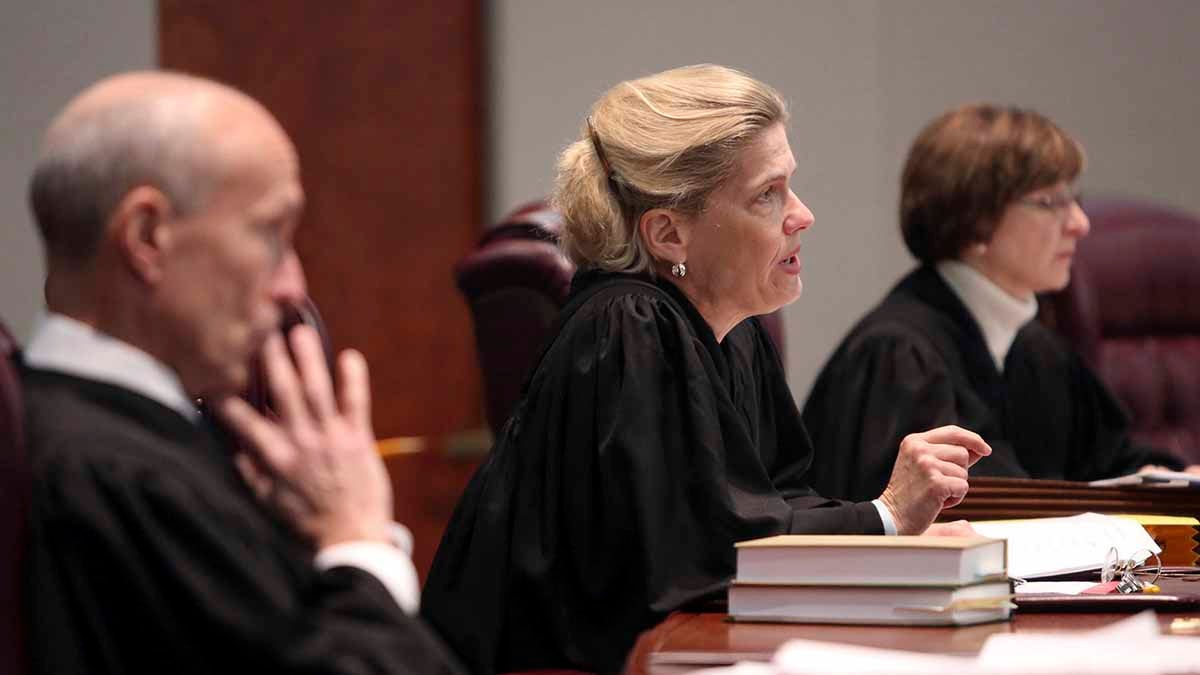A row of judges are seated at a table.