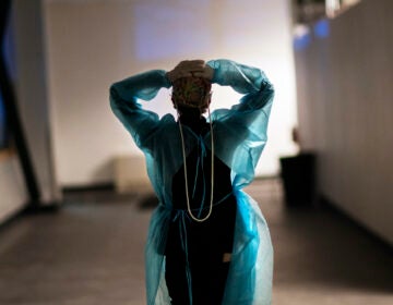 A nurse walks down a hallway with her arms in the air, clasping the back of her head