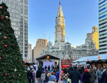A Christmas tree is visible in the foreground, with Philadelphia City Hall in the background.