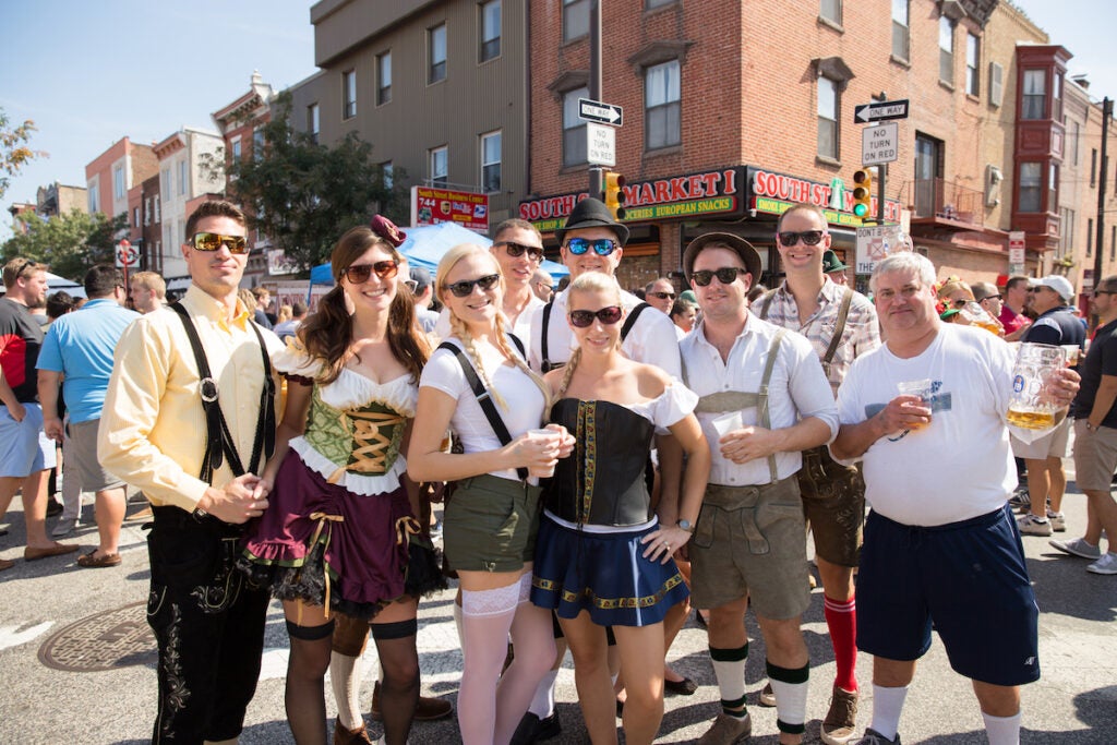 People posing for a photo on South Street dressed in traditional German attire.