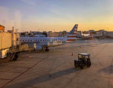 An airplane is seen pulling up to a gate at sunset.