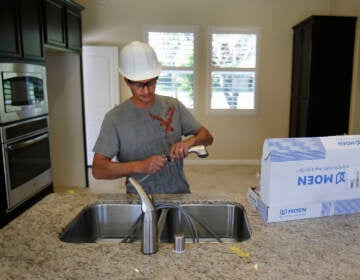 A plumber installs a kitchen faucet on a home under construction in Sacramento, Calif. (AP Photo/Rich Pedroncelli)
