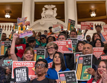 Many people holding signs inside the Capitol building.
