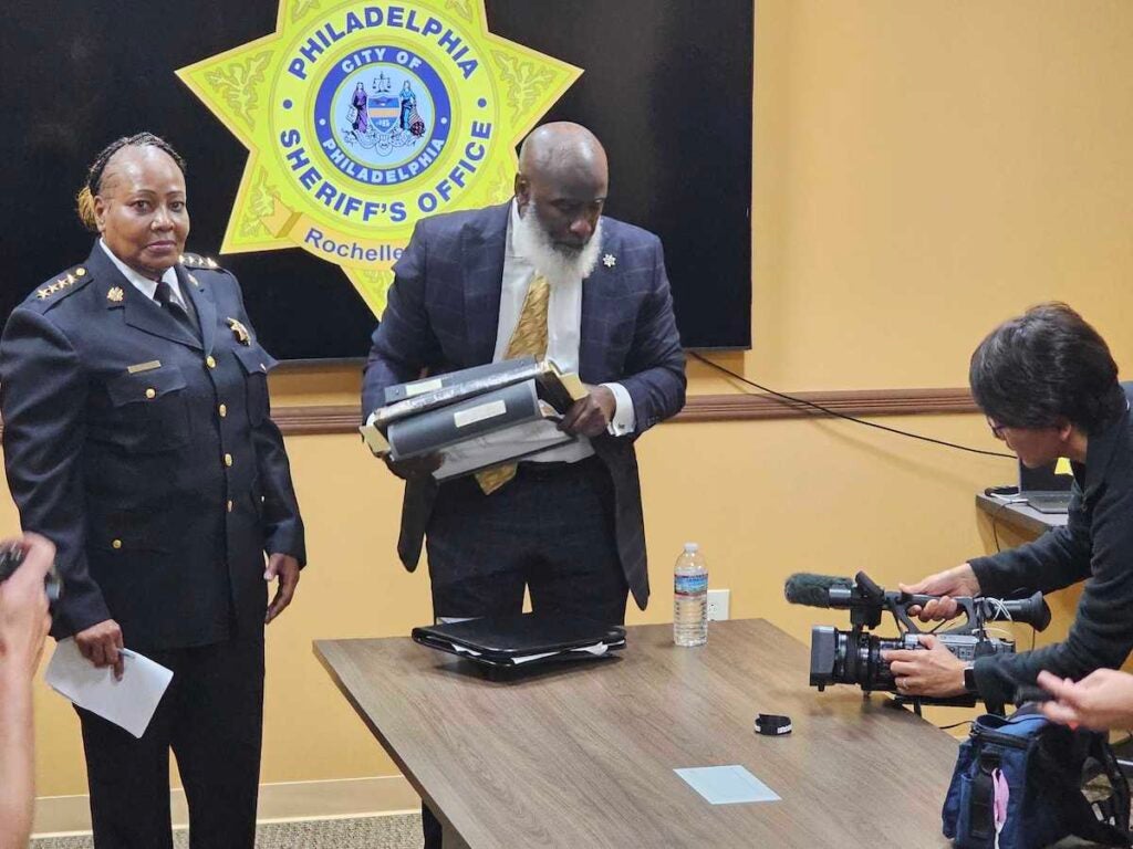 Sheriff Rochelle Bilal stands next to Undersheriff Tariq El-Shabazz who is holding a binder.