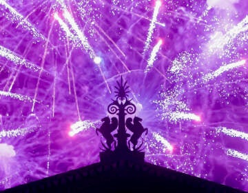 Fireworks explode in the background behind a gargoyle atop of the central portico of the Philadelphia Museum of Art