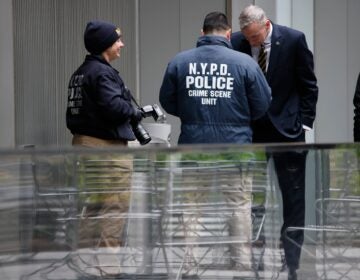 Members of the New York police crime scene unit investigate the scene outside the Hilton Hotel