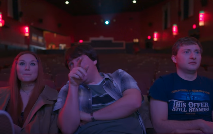 Three people sit in a theater