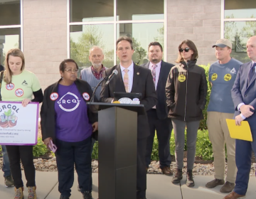 Multiple people standing at a podium for a press conference